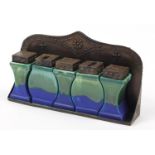 Arts & Crafts design embossed copper rack with five ceramic jars, each having a blue and green