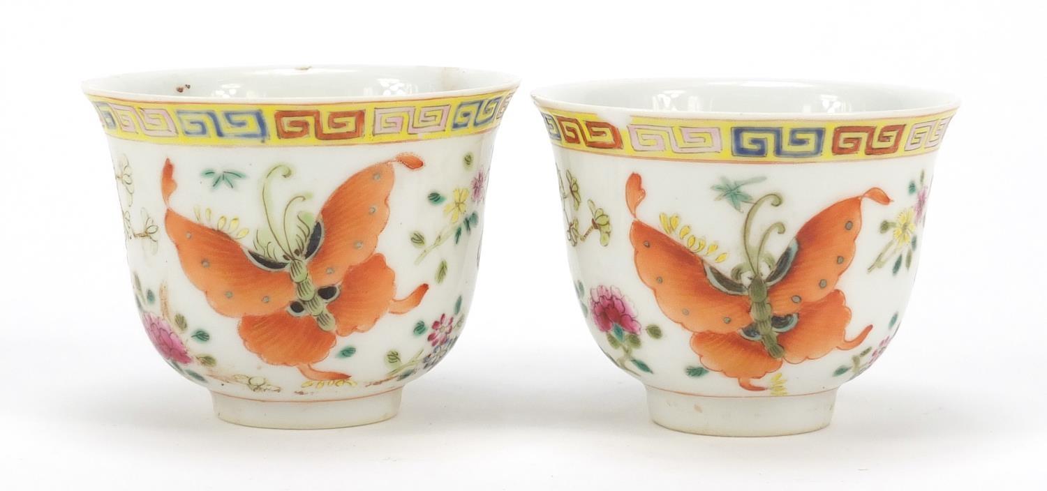 Pair of Chinese porcelain tea cups, each finely hand painted in the famille rose palette with