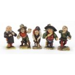 Five 19th century Continental porcelain dwarfs, factory marks to the bases, the largest 9cm high