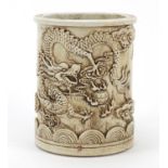 Chinese monochrome white porcelain cylindrical brush pot, decorated in relief with a dragon