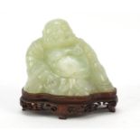 Chinese carved green jade Buddha raised on carved hardwood stand, 11.5cm wide