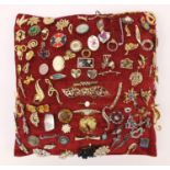 Costume jewellery brooches arranged on a cushion including enamel examples