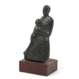 Modernist greenstone carving of a mother and child raised on a rectangular hardwood base, 27cm high