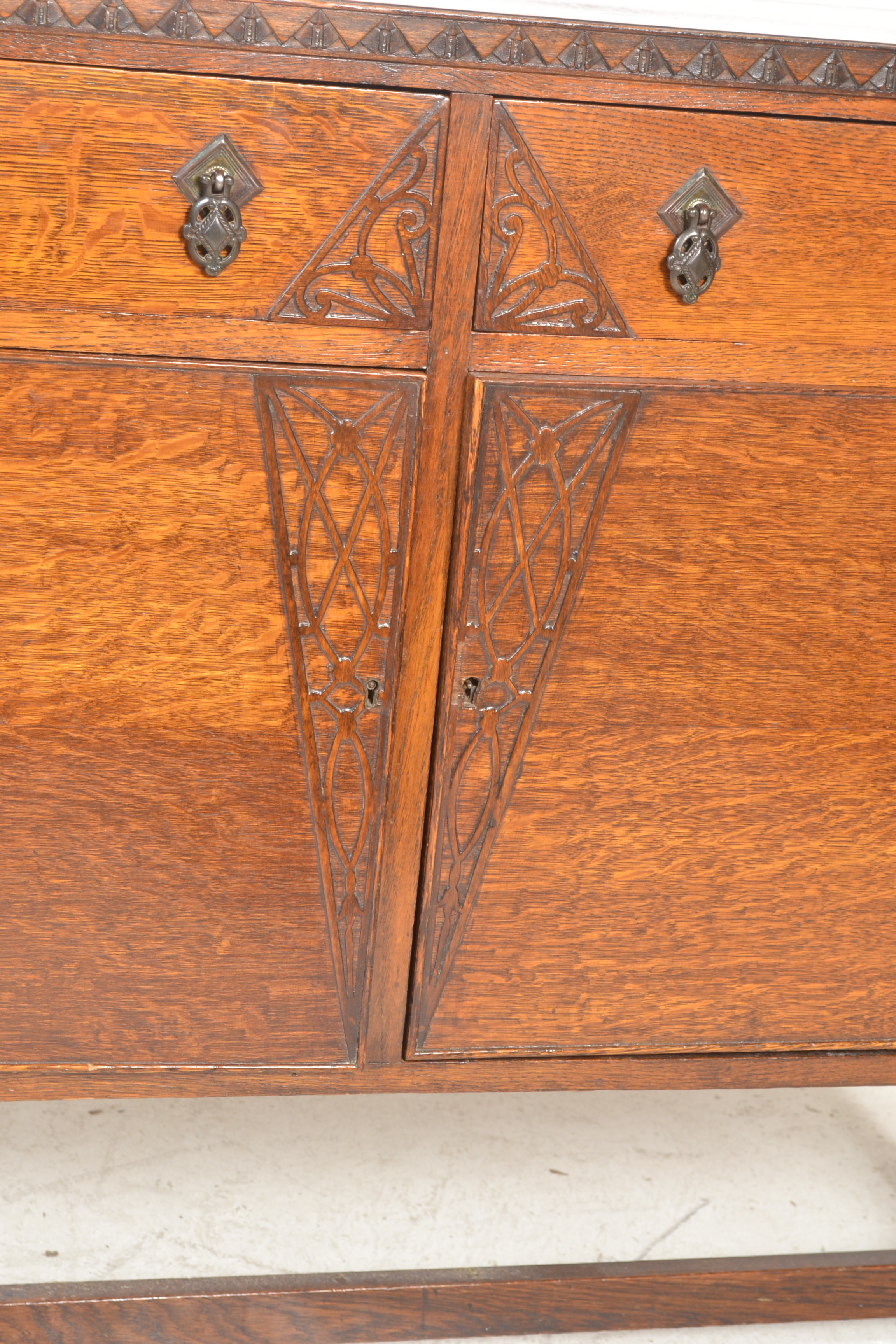 A 1930's oak sideboard being raised on cup and cover legs having twin cupboard doors under short - Image 2 of 6