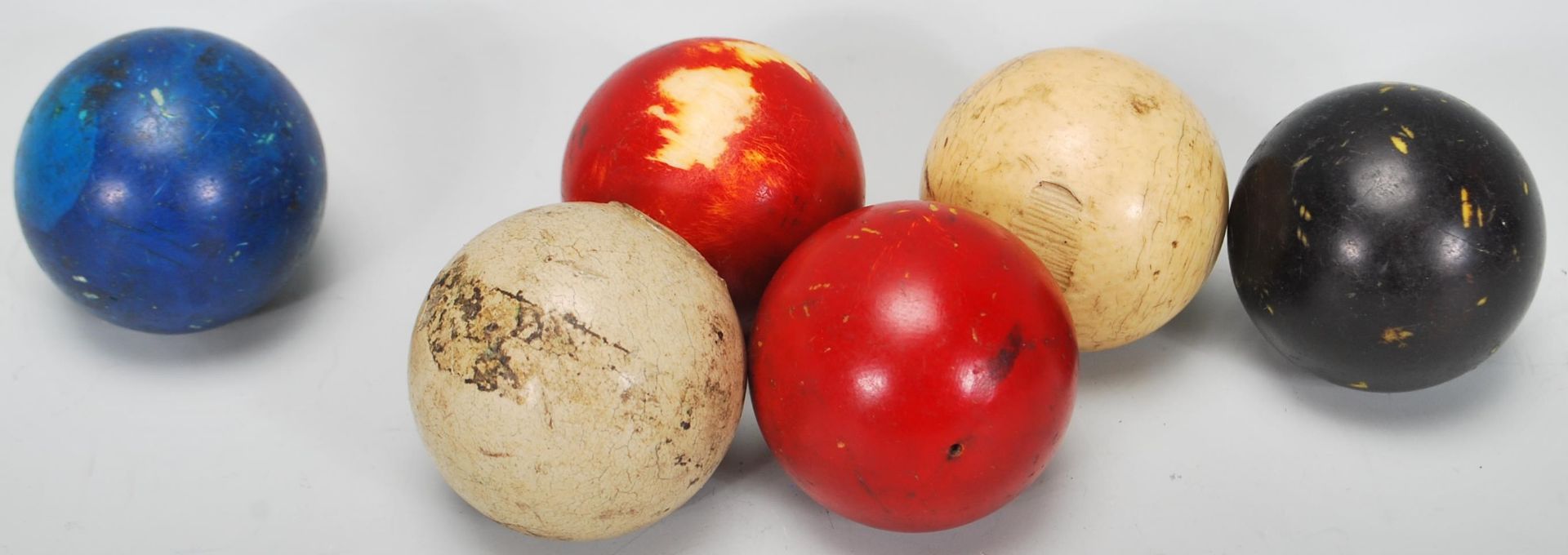A group of five antique ivory snooker balls. Colours include one white ball, blue and black balls