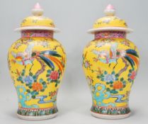 A pair of early to mid 20th Century Chinese Famille Jaune lidded urn vases and covers with enamelled