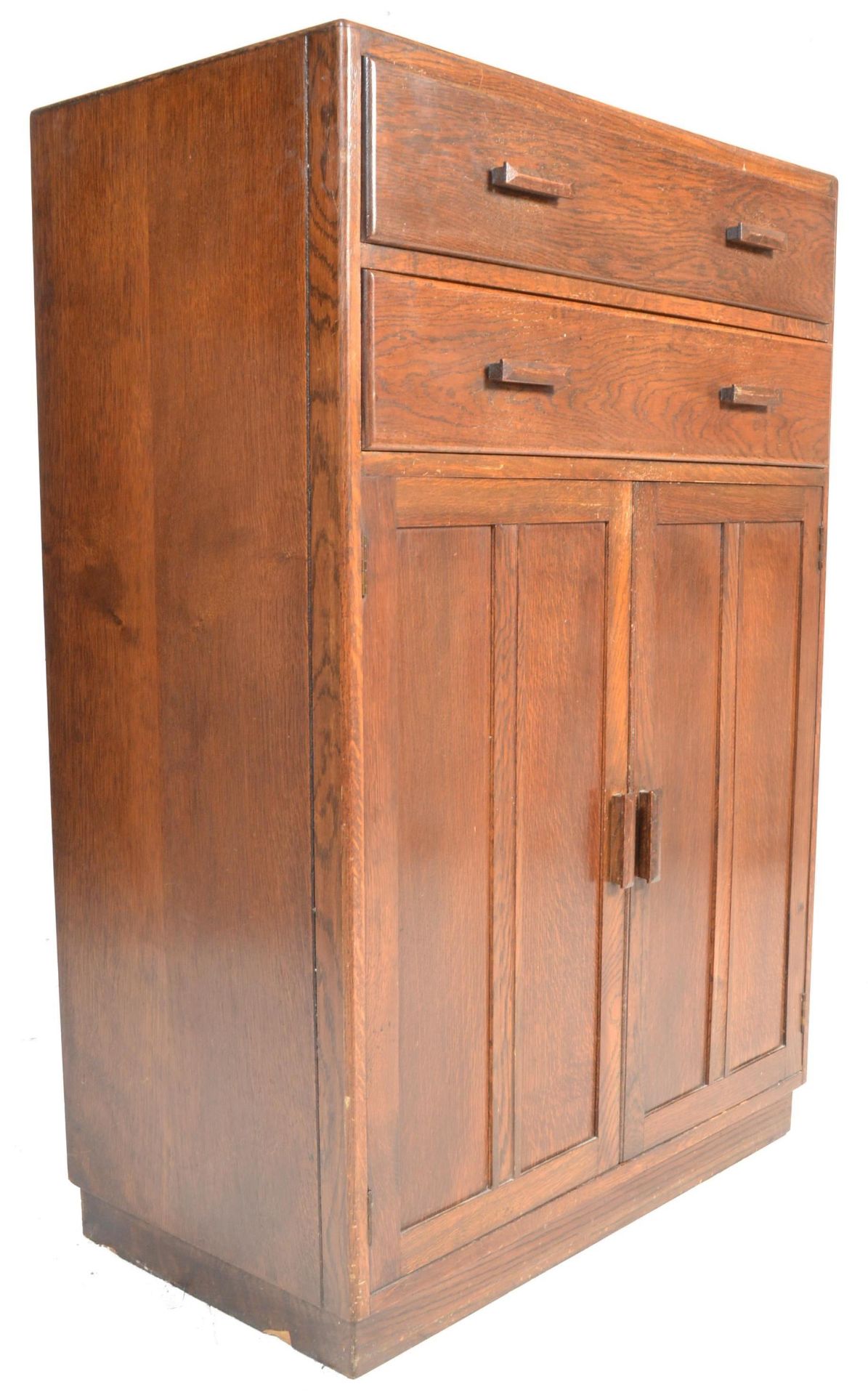 A mid century circa 1940's oak tallboy raised on a plinth base with twin cupboard and two drawers