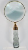 A large brass mounted hand held magnifying glass having a faceted glass cut handle. Measures 23cm