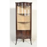An Edwardian mahogany display cabinet, free standing and enclosed by a single serpentine shaped