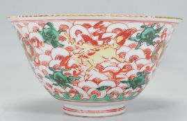 A Chinese centrepiece bowl of footed flared form being hand painted with florals and mythical beasts