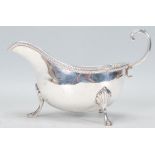 An early 20th century Edwardian Charles and George Asprey silver gravy boat raised on claw feet with