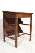 A 1920's oak school desk of good quality raised on squared legs having twin book trough shelves to
