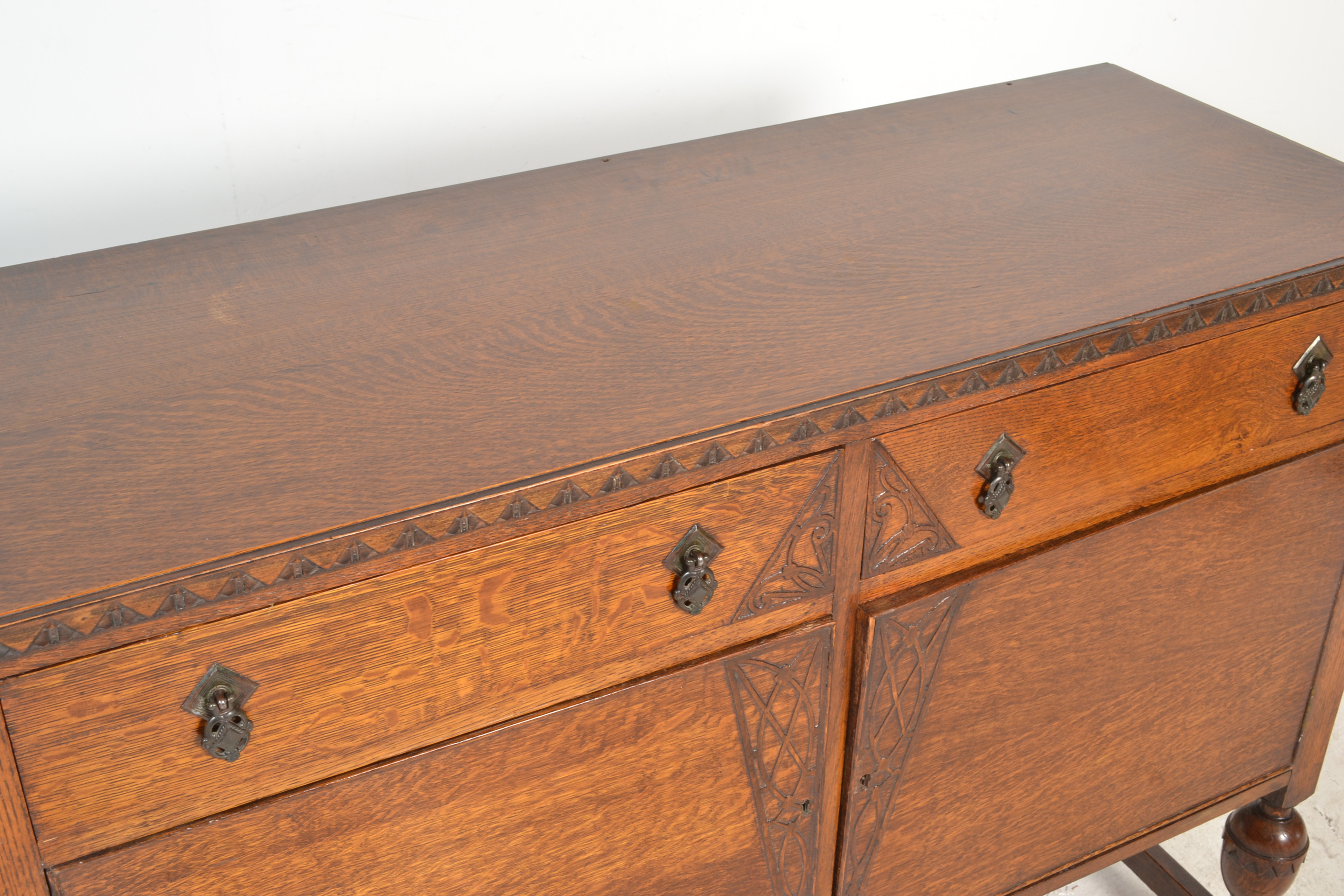 A 1930's oak sideboard being raised on cup and cover legs having twin cupboard doors under short - Image 4 of 6