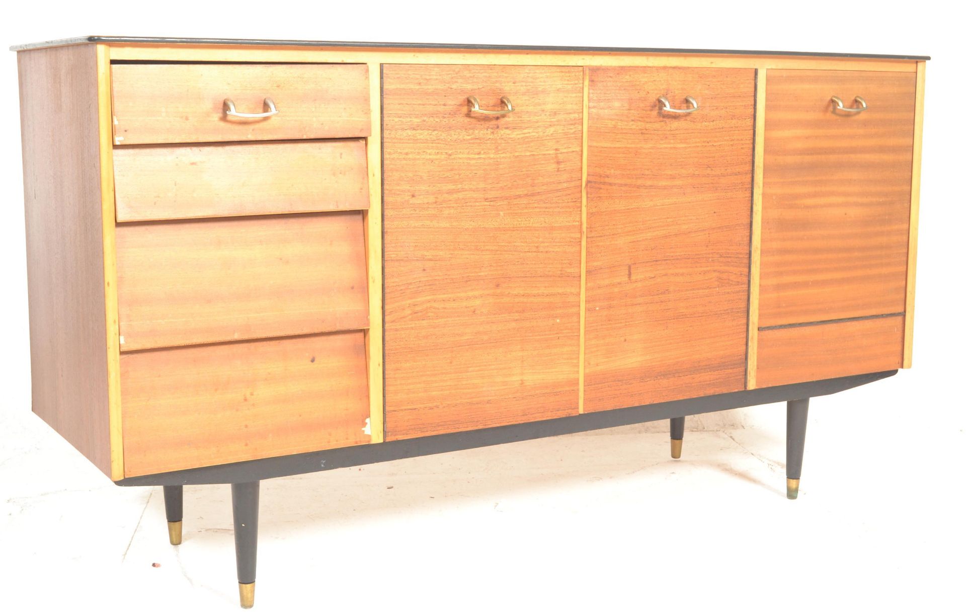 A retro mid century teak wood sideboard credenza being raised on turned legs with a wide body