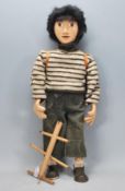 A vintage 20th Century hand made wooden puppet moulded as young boy having a violin and backpack.