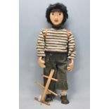 A vintage 20th Century hand made wooden puppet moulded as young boy having a violin and backpack.