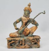 A 20th Century Indian brass figure of Saraswati the Hindu deity, modelled playing the sitar raised