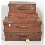 A stack of four vintage early 20th century leather suitcases / trunks to include various sizes,