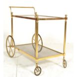 A mid century italian brass and smoked glass trolley table raised on original castors having twin