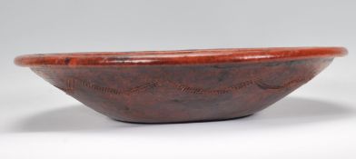 An early 20th Century Japanese terracotta wall charger of simple form having engraved pattern rim.