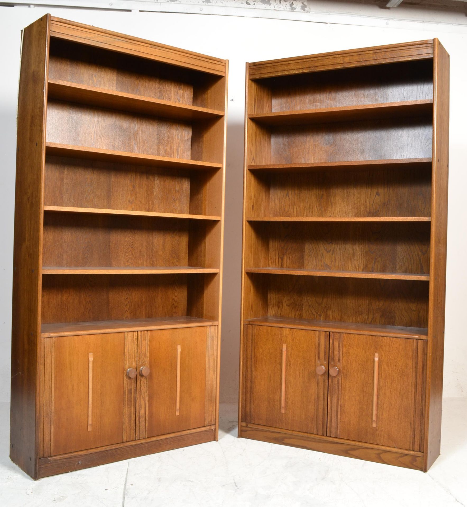 A pair of retro 1970's oak upright library bookcase cabinets. Rasied on plinth base with double door