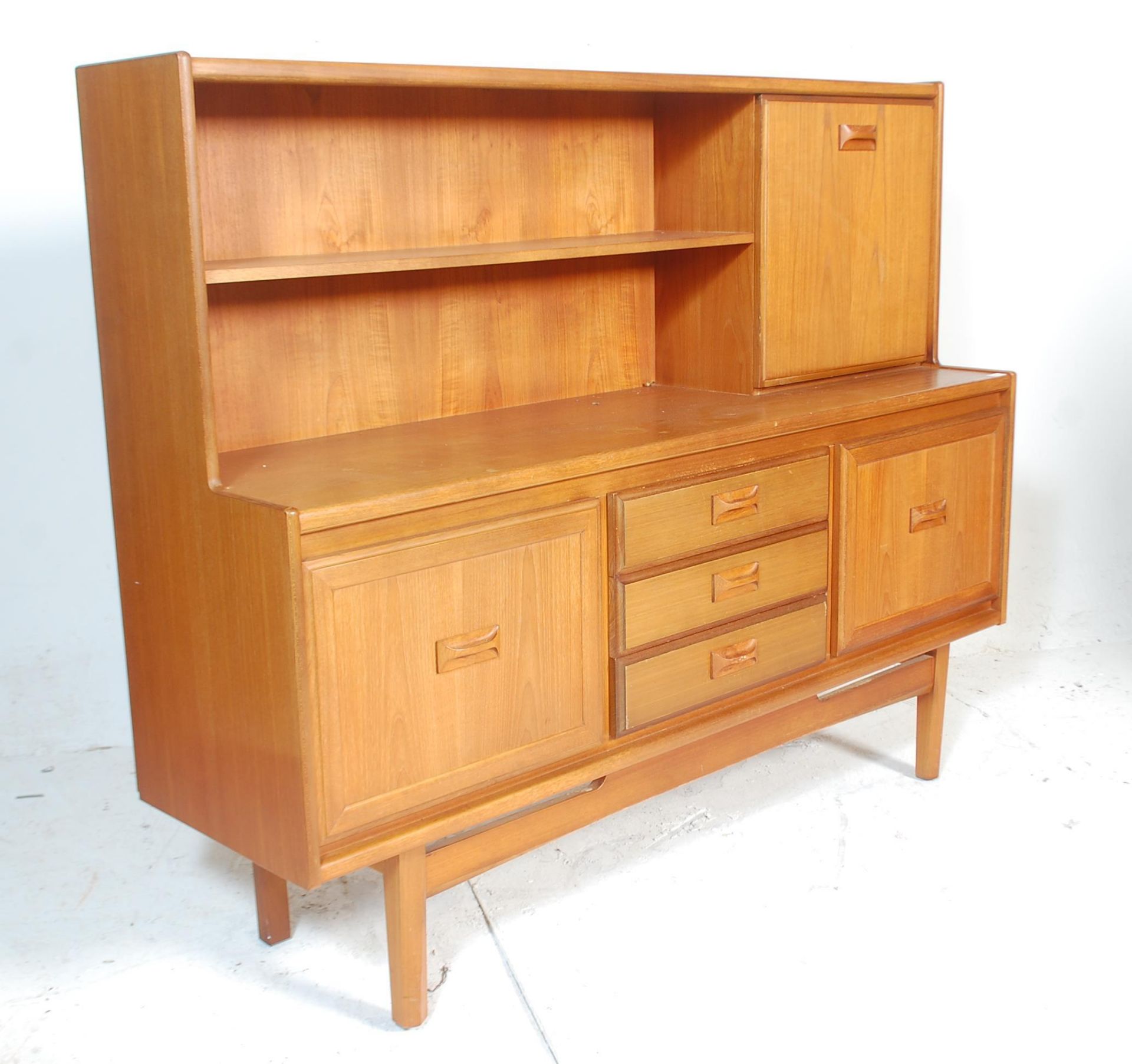 A 20th Century retro teak wood highboard sideboard credenza, having a configuration of three central