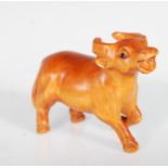 A Japanese boxwood netsuke in the form of a yak having glass set with glass eyes. Signed to