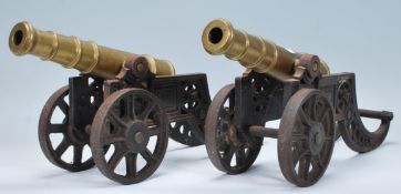 A pair of 20th Century brass desk top ornaments in the form of cannons raised on tilting twin