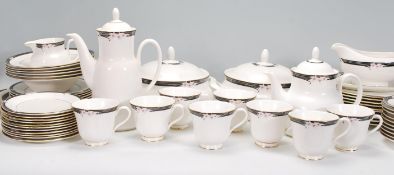 A vintage Royal Doulton Vogue Collection 'Enchantment' china dinner service, having a white ground