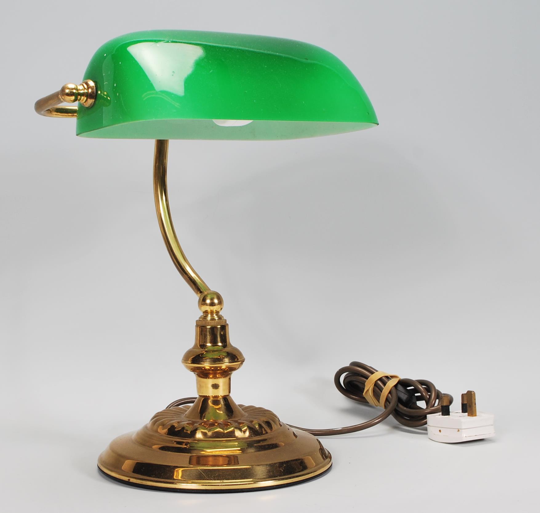 A vintage 20th Century bankers desk lamp having an adjustable green glass shade raised on a brass