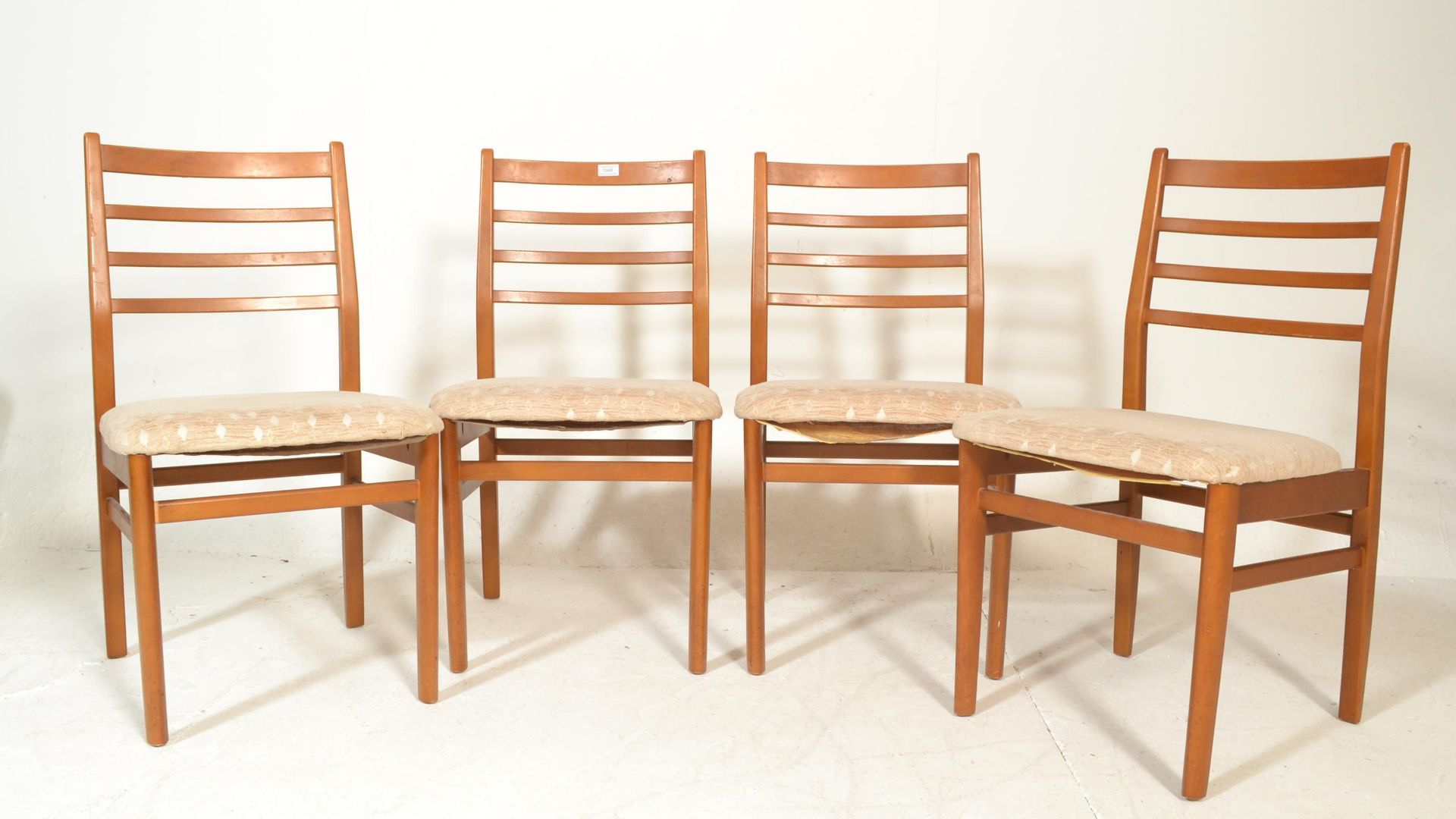 A set of four retro 20th Century teak wood rail back dining chairs, upholstered seat pads raised