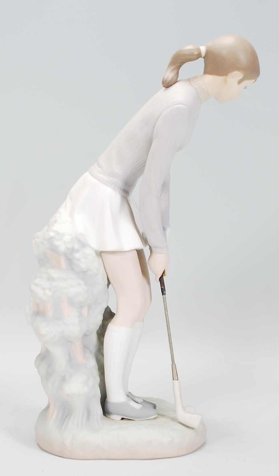 A ceramic Lladro figurine in the form of a lady golfing raised on a naturalistic base. Measures 27cm - Image 2 of 6