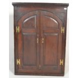 A 19th Century Georgian mahogany hanging corner cabinet twin panelled arched doors opening to reveal