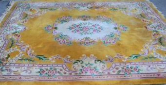 A large Chinese floor rug with  yellow ground and floral decoration to the centre with tasseled