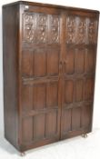 A large mid century Jacobean revival oak double wardrobe armoire. Raised on ball castors with twin