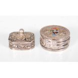 A silver white metal pill box having a hand decorated cockerel atop the hinged lid with repousse