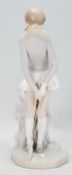 A ceramic Lladro figurine in the form of a lady golfing raised on a naturalistic base. Measures 27cm