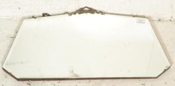 An early 20th Century frameless bevelled edged mirror having decorative brass swag moulded top and