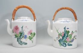 A pair of large Chinese polychrome teapots of cylindrical form having floral sprays to each with