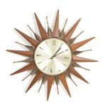 An original retro vintage Metamic starburst teak and brass wall clock with quartz movement. Measures