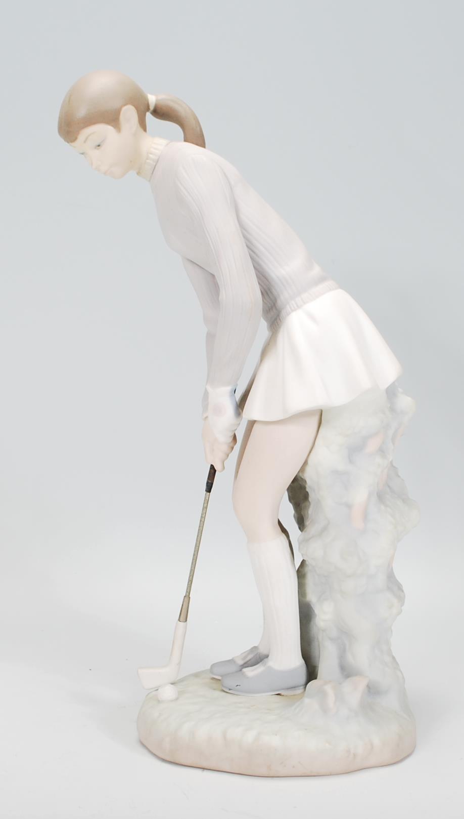 A ceramic Lladro figurine in the form of a lady golfing raised on a naturalistic base. Measures 27cm - Image 4 of 6