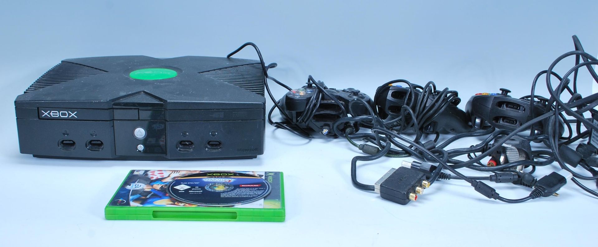 An original Xbox games console together with with three Xbox controllers, cables and The Sims.