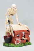 A novelty cast iron clockwork novelty money box in the form of a skeleton sawing the head off