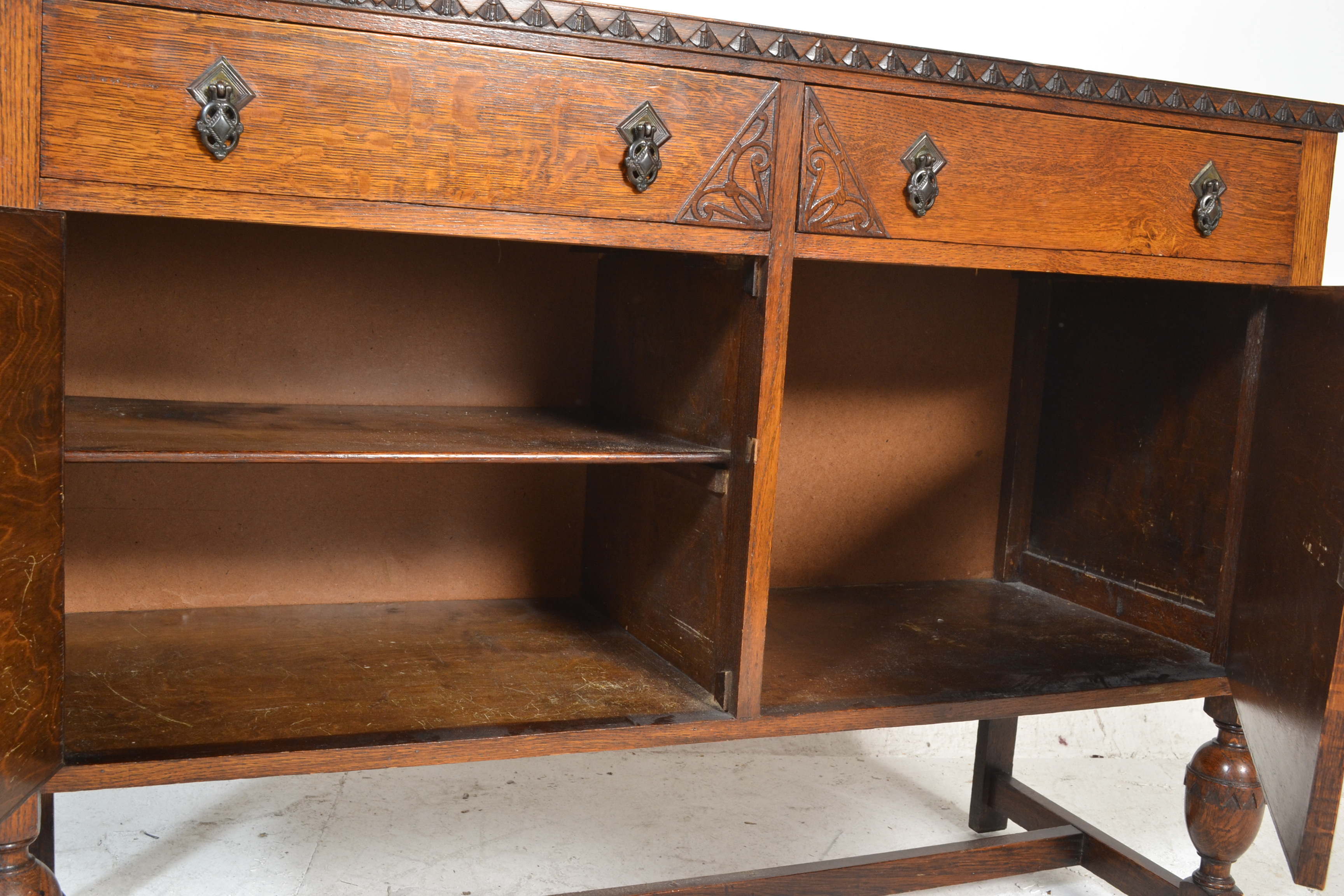A 1930's oak sideboard being raised on cup and cover legs having twin cupboard doors under short - Image 6 of 6