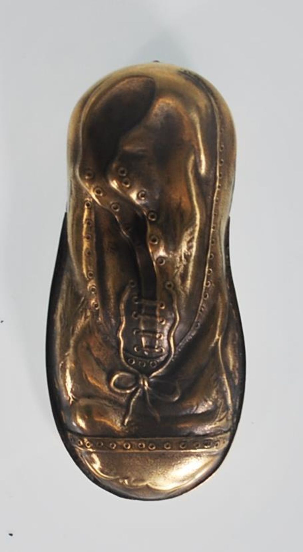 A brass vesta case in the unusual form of a shoe. The case features detail such as shoe laces and