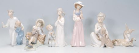 A group of four Lladro porcelain figures to include a young leaning on a log with a bird upon his