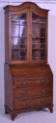 An Edwardian solid oak bureau bookcase raised on shaped supports having a  bank of drawers beneath