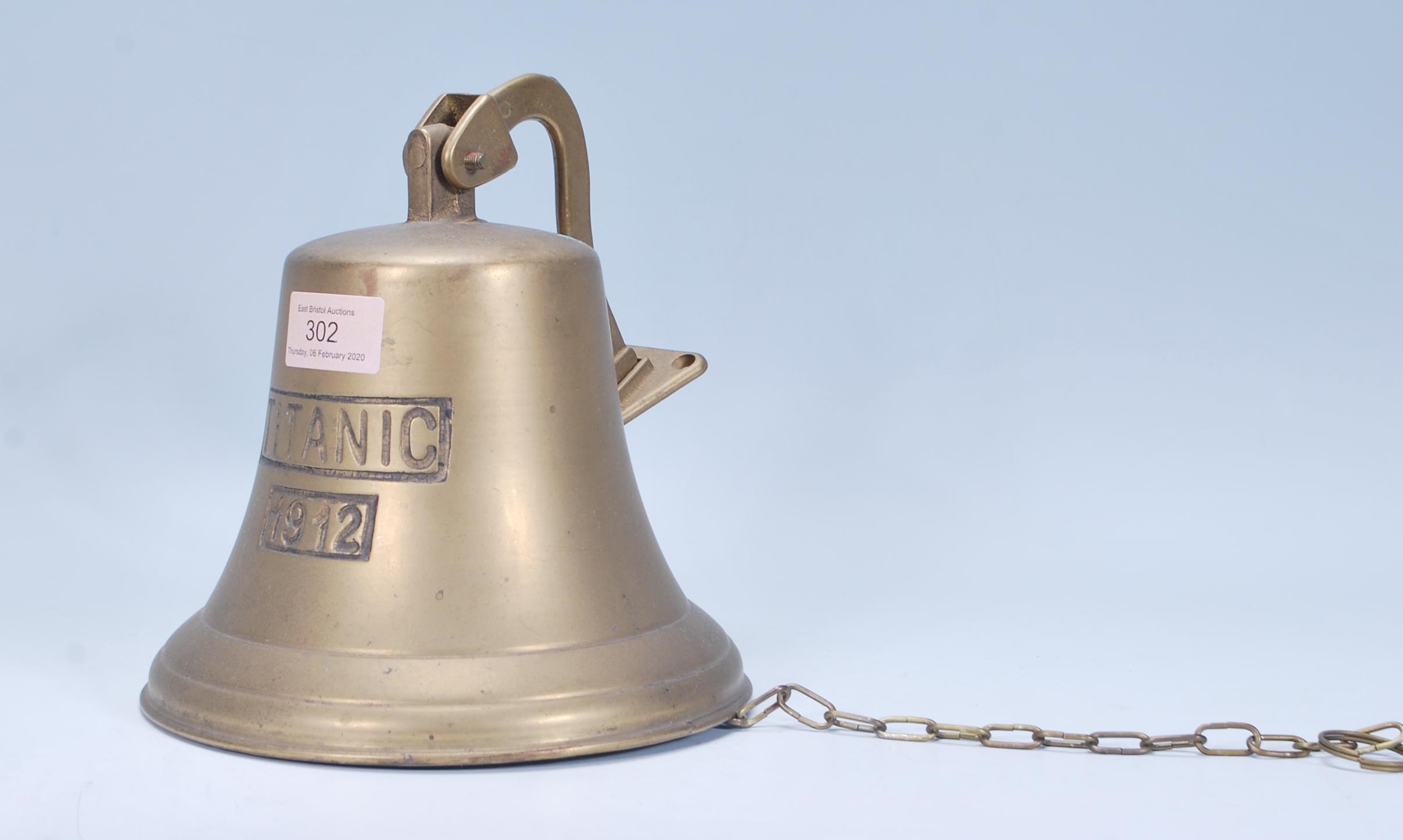 A 20th Century wall mounting brass bell marked Titanic 1912, having a chain attached to the clanger.