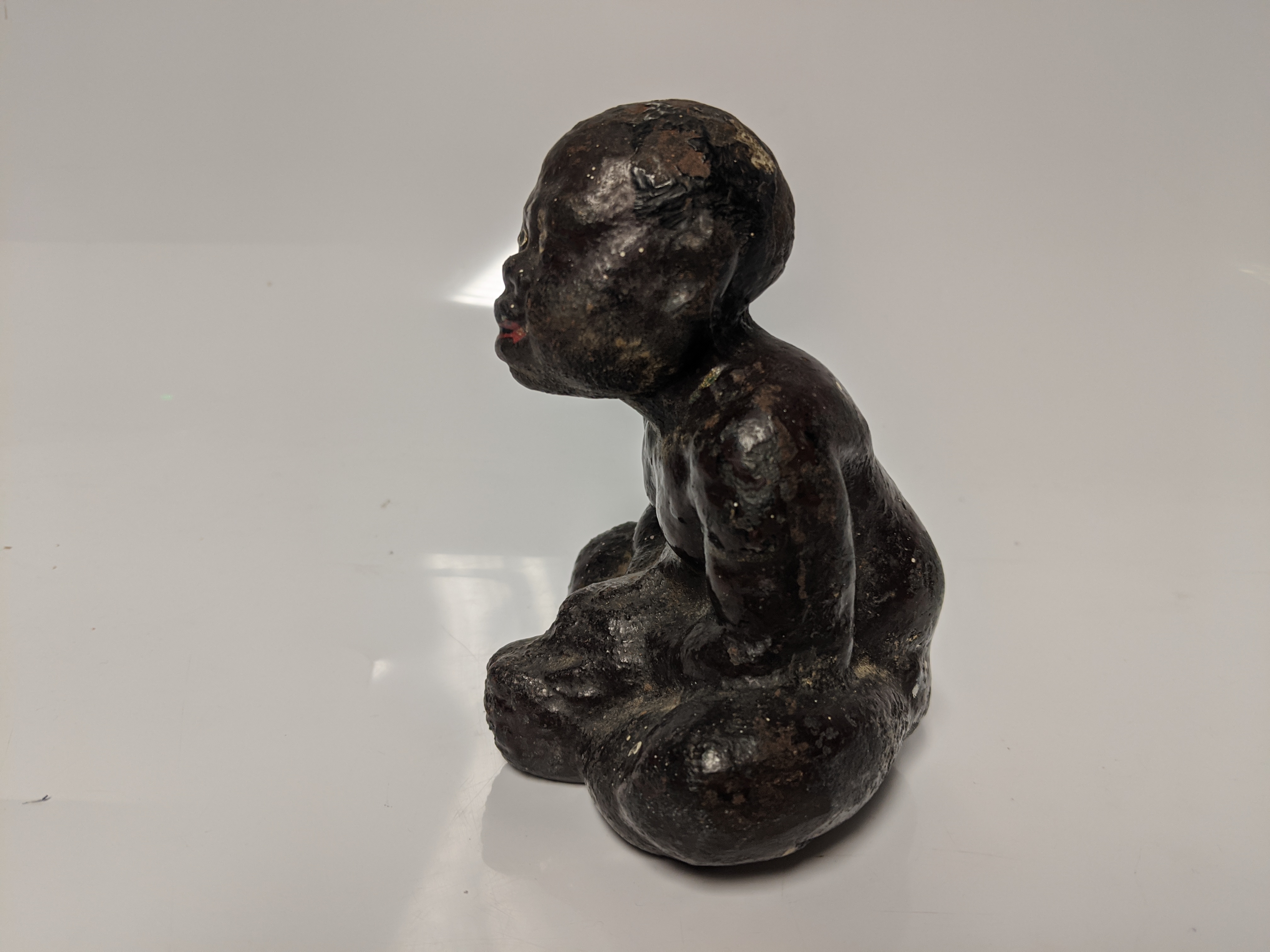 An early 20th century cast iron Black Americana paperweight / figurine of a seated male figure being - Image 4 of 5