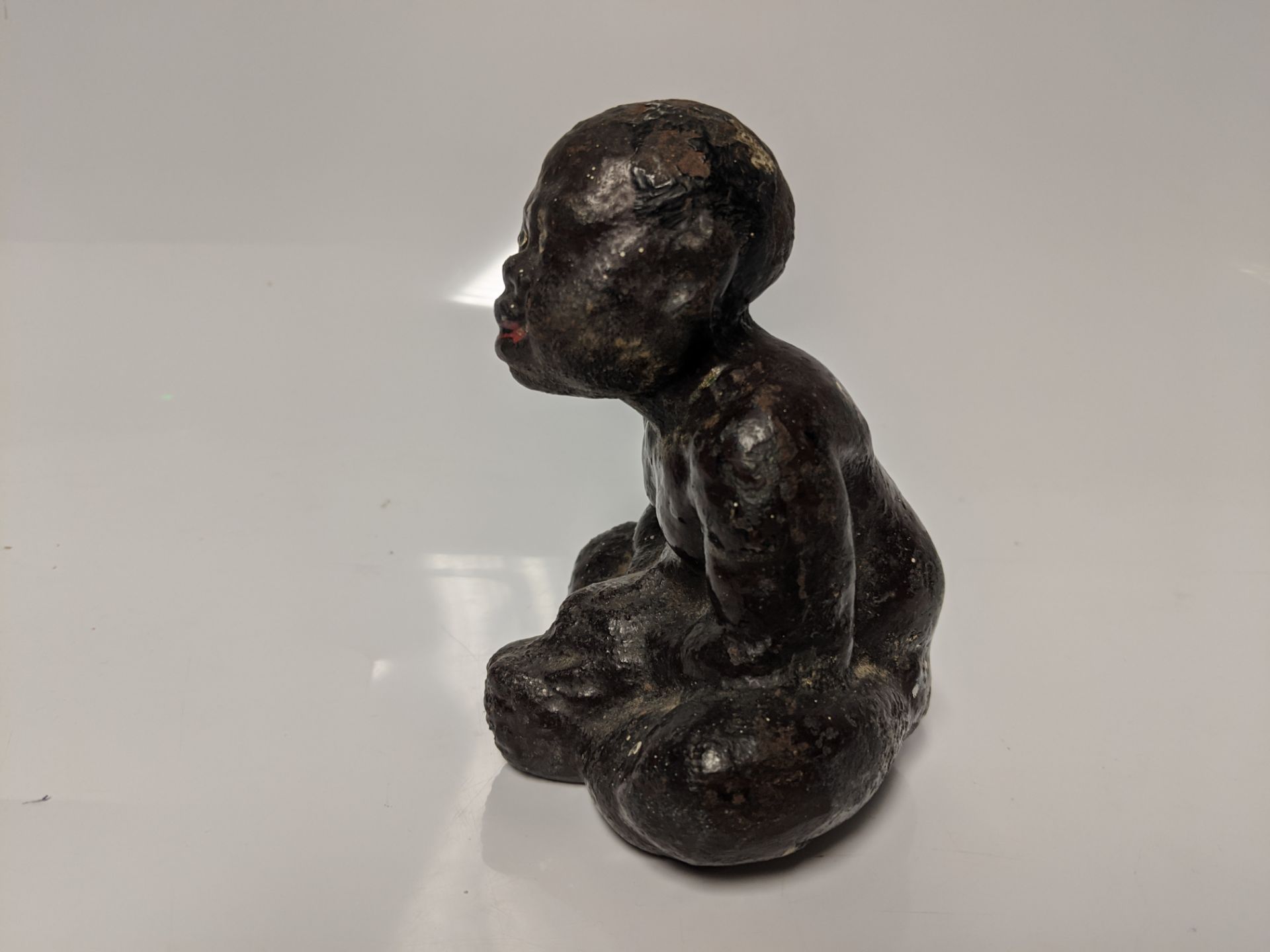 An early 20th century cast iron Black Americana paperweight / figurine of a seated male figure being - Bild 4 aus 5